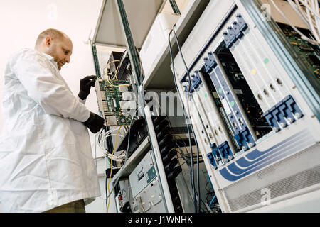 Tecnico operante nella scheda di rete labaratory Foto Stock