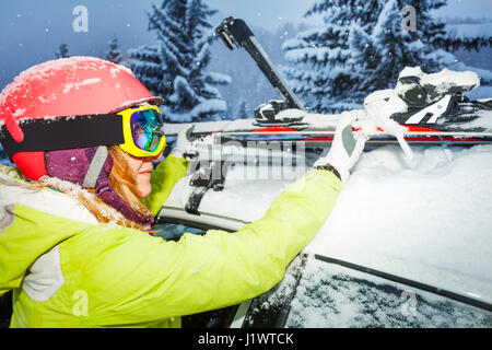 Close-up ritratto femminile di sciatore sci di fissaggio alle guide del tetto della vettura dopo il viaggio di sci di montagna Foto Stock