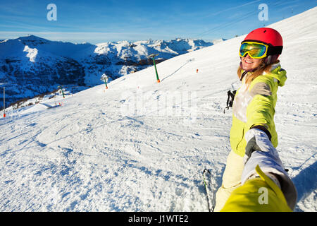Donna sorridente sciatore tenendo selfie dall alto angolo contro la splendida vista delle montagne innevate Foto Stock
