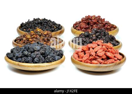 Assortimento di frutti di bosco essiccati in ciotole di legno isolato su sfondo bianco Foto Stock