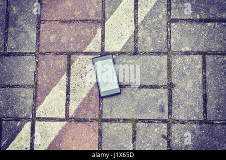 Telefono cellulare con schermo rotto su un street, tonificazione del colore applicato, vista dall'alto. Foto Stock