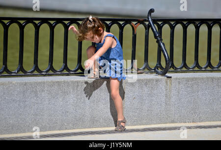 Una bambina scendendo una recinzione. Parque del Retiro di Madrid, Spagna Foto Stock