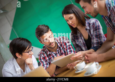 Un gruppo di studenti che studiano in un cafè con un tablet Foto Stock