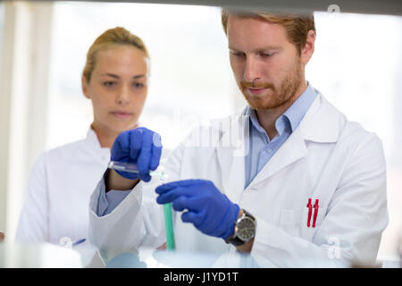 Giovane farmacista al lavoro miscelazione liquidi in laboratorio Foto Stock