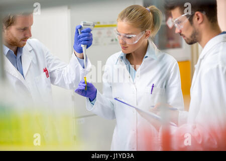 Team di esperti in laboratorio chimico mettere il campione di liquido nella pipetta di prova Foto Stock