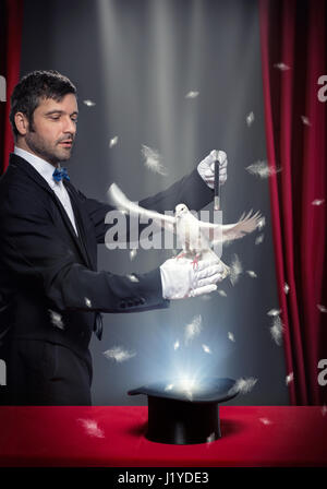 Il mago di eseguire la magia al piccione sul palco teatrale Foto Stock