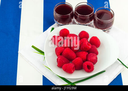 Fresche Lamponi rosso su bianco artistica targa / rosso dei lamponi freschi su un bianco artistica targa con i cookie, rosmarino, cioccolato e crema di panna in b Foto Stock