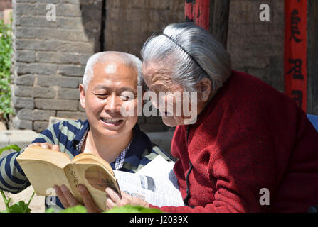 Sanmenxia, la Cina della Provincia di Henan. 23 apr, 2017. Il 95-anno-vecchio Wei Zuhe (R) e il suo 59-anno-vecchio figlio di leggere un libro nel villaggio di Qianqiu di Yima City, centrale cinese della Provincia di Henan, 23 aprile 2017. La Giornata Mondiale del Libro cade di domenica. Credito: cui Chang/Xinhua/Alamy Live News Foto Stock