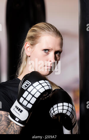 Giovane donna tatuata, boxe a sandsack in un boxing studio, Baviera, Germania Foto Stock