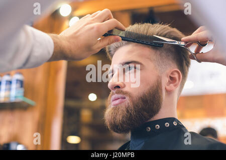Giovane uomo nel negozio di Barbiere per la cura dei capelli il concetto di servizio Foto Stock