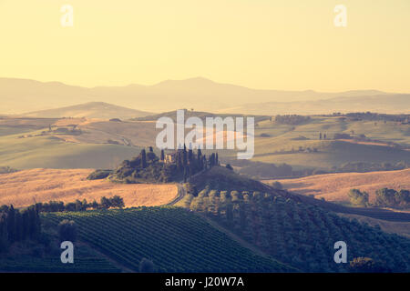 Visualizzazione classica di scenic paesaggio toscano con la famosa casa colonica in mezzo idilliache colline e valli in beautiful Golden. La luce del mattino al sunrisei Foto Stock