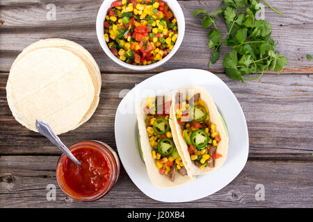 Carni bovine il mais soft taco su tavola in legno rustico con salsa di mais Foto Stock