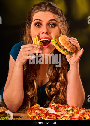 Donna di mangiare patatine e hamburger sul tavolo. Foto Stock