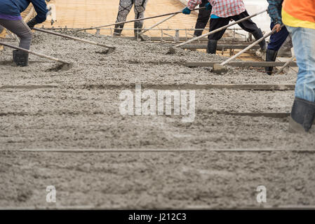 Lavoratori edili sono tramite il nuovo versata spanditori di cemento nel terreno per consentire il normale calcestruzzo di cemento con uno spessore determinato dal Foto Stock