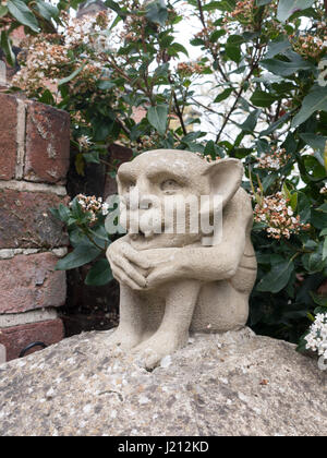 Una strana goblin gremlin statua in calcestruzzo su un montante esterno con zanne e grandi orecchie creepy scary odd Foto Stock