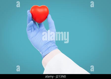 Medico con cuore giocattolo in mano - studio shot su fondo azzurro Foto Stock