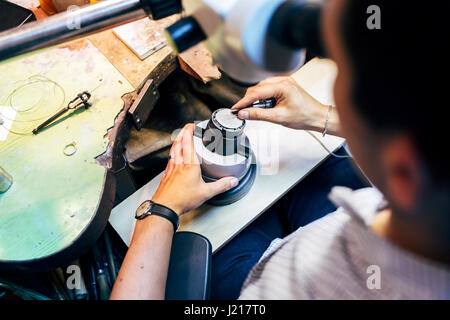 Gioielliere lavorando su metalli con dispositivo ottico che consente per lavori di precisione Foto Stock