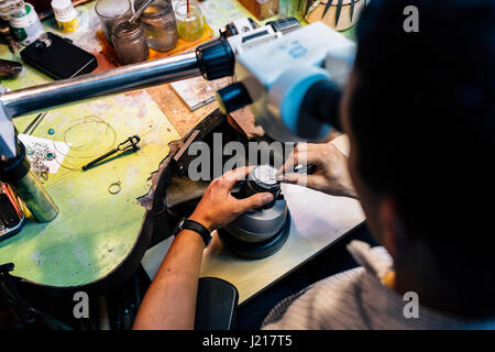 Gioielliere lavorando su metalli con dispositivo ottico che consente per lavori di precisione Foto Stock