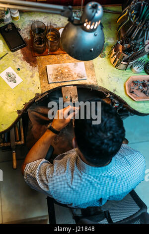 Artigiano lavorando su un banco di lavoro circondato dai suoi strumenti Foto Stock