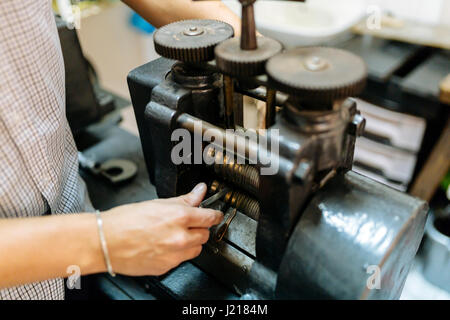 Goldsmith creazione di metallo con l'aiuto di una pressa Foto Stock