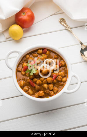 Piccante di ceci curry o Chola Masala o Chana Masala o chole bhature o choley guarnita con la cipolla tagliata a fettine e verde foglia di coriandolo, focu selettiva Foto Stock