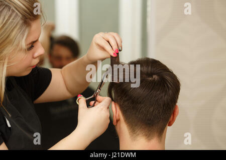 Parrucchiere professionale facendo taglio maschile di capelli. Taglio di capelli con le forbici. Salone di bellezza. Bellezza maschile. Il client è un hipster. Foto Stock