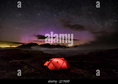 Campeggio selvaggio su estremità di confine nel Lake District inglese, UK. 23 Aprile, 2017. Le luci del nord torre oltre la gamma Scafell in background. Foto Stock