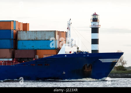 Contenitore blu della nave contro la prua grande faro, Lettonia Foto Stock