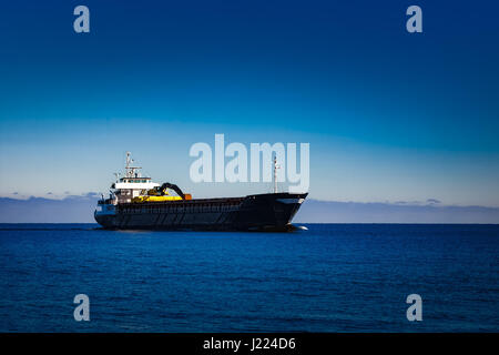 Nero nave cargo con long reach escavatore muovendo dal mar baltico Foto Stock