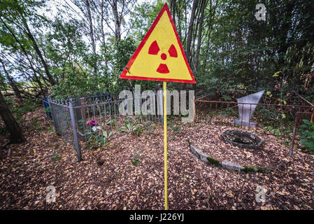 Radiazioni ionizzanti segno di avvertimento su un cimitero di pripjat città fantasma della centrale nucleare di Cernobyl la zona di alienazione in Ucraina Foto Stock