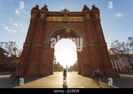 Barcellona, Spagna - 6 Gennaio 2017: l'Arc de Triomph con un ciclista che sta attraversando l'arco in primo piano, la mattina di sole Foto Stock