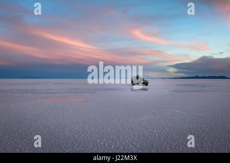 Veicolo fuoristrada all'alba nel Salar de Uyuni distesa di sale - dipartimento di Potosi, Bolivia Foto Stock
