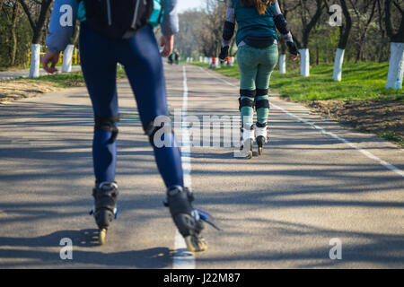 Due ragazze su pattini a rotelle corrono lungo la strada accanto a ciascun altro Foto Stock