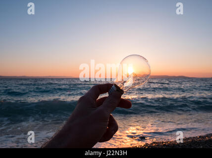 Uomo con lampadina contro il sole sul concetto di spiaggia Foto Stock