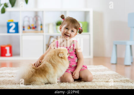 Carina ragazza del bambino seduto sul pavimento con il suo cane Foto Stock