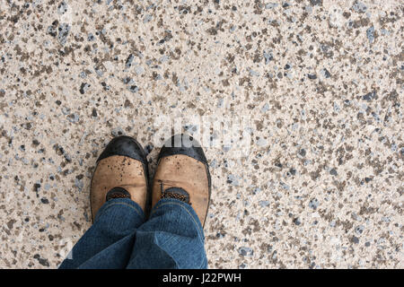 Gli uomini le gambe in presenza di sporco sport sneakers sul vecchio asfalto con gocce di pioggia, vista dall'alto Foto Stock