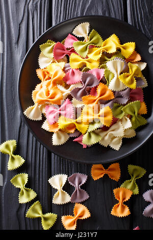 Materie italiano farfalle multicolori pasta close-up sul tavolo. Vista verticale da sopra Foto Stock