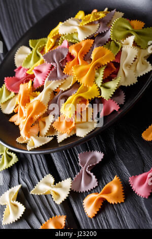 Materie italiano farfalle multicolori pasta close-up sul tavolo. In verticale Foto Stock