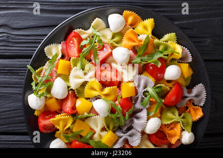 Il cibo italiano: farfalle di pasta con verdure e mozzarella close-up su una piastra orizzontale di vista da sopra Foto Stock