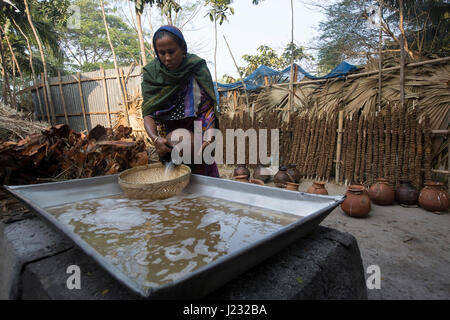 Una donna si riversa data succo di Palm sul piatto per produrre la melassa. Jessore, Bangladesh. Foto Stock