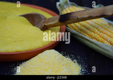 Mucchio di grano macinato, polenta e un tutolo di mais collocato sul tavolo di legno nella luce naturale Foto Stock