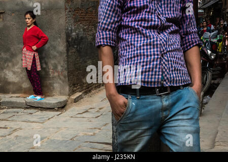 Ragazzo adolescente permanente sulla strada con una donna in background, Patan Nepal. Foto Stock