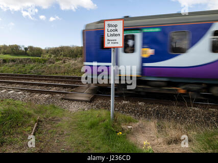 Treno che supera un attraversamento pedonale cartello segnaletico, Silverdale Lancashire, nord-ovest, in Inghilterra, Regno Unito Foto Stock