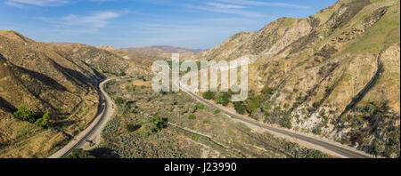 I binari della ferrovia e strada asfaltata corrono in parallelo attraverso una vallata desertica. Foto Stock