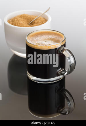 Expresso nero / caffè espresso nella piccola coppa di vetro con lo zucchero nella ciotola bianco Foto Stock