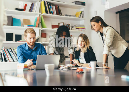 Il brainstorming i colleghi seduti alla scrivania in ufficio e la condivisione di idee Foto Stock