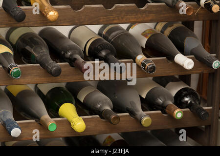 Dettaglio colpo di polverose bottiglie di vino in un vino in legno rack Foto Stock