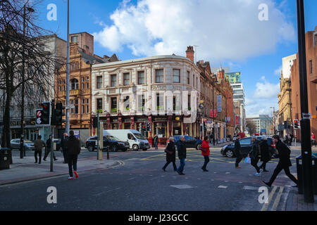 Strada di Manchester, UK con persone sconosciute che attraversa la strada e il tradizionale Segatori Arms pub all'altro lato di Deansgate street. Foto Stock