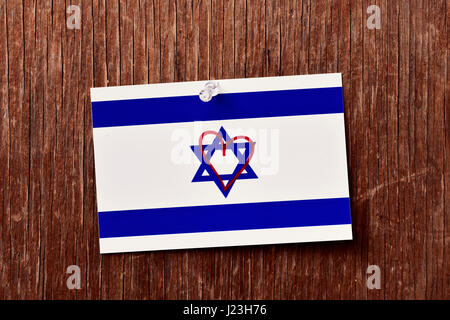 Primo piano di una bandiera di Israele con un cuore disegnato in essa riposte con un push-pin a un rustico sfondo di legno Foto Stock