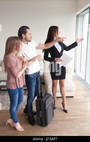 Coppia giovane con custodia da viaggio incontro con broker, appartamento vie Foto Stock